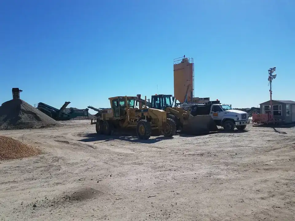 A CAT motor grader, wheel loader and service truck parked near the silo and scale house