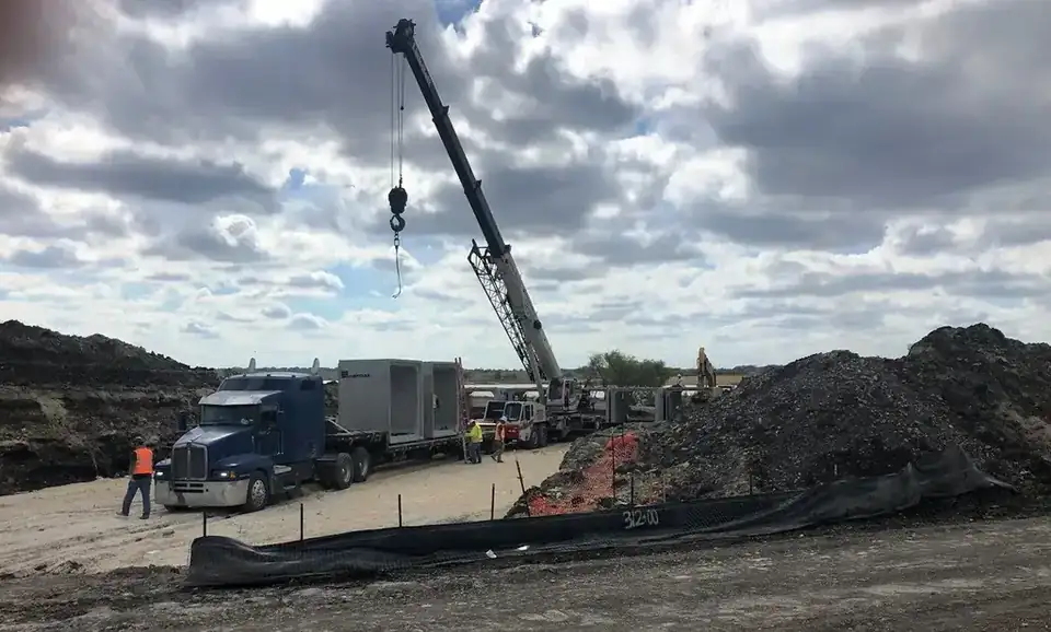 A mobile crane setting a precast box culvert section off a lowboy, silt fence in the foreground stencilled 312+00