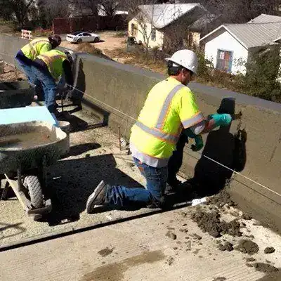 Two men hand-finishing a curb with a float and a mortar tub