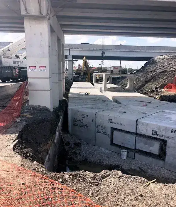 Box culvert runs stencilled AC-42 Aaron Concrete, set beneath a live highway overpass