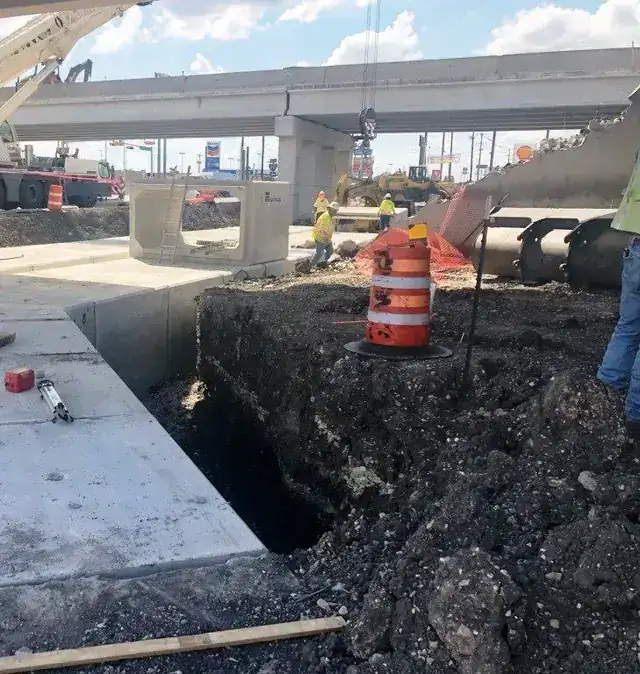 The same box culvert job: a culvert run and a sawcut asphalt trench with a crew working