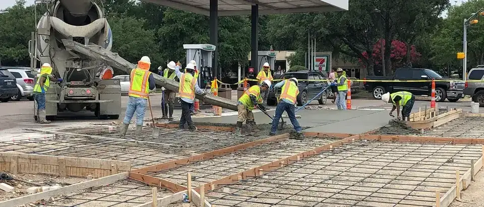 A ten-man Aaron Concrete crew raking and screeding a fresh pour at an Austin intersection