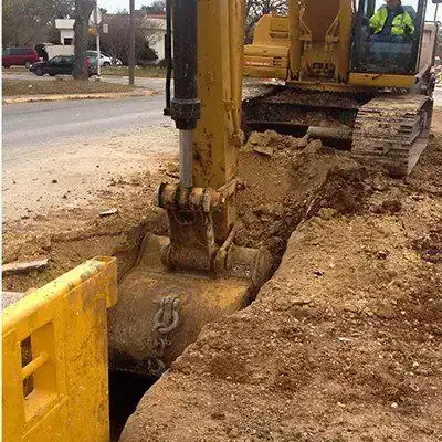 An excavator bucket working a trench, close